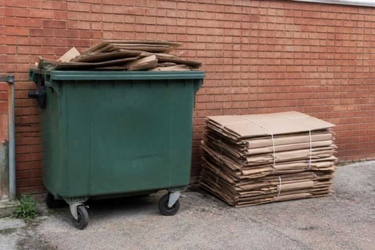 Rolcontainer met karton achter een winkel